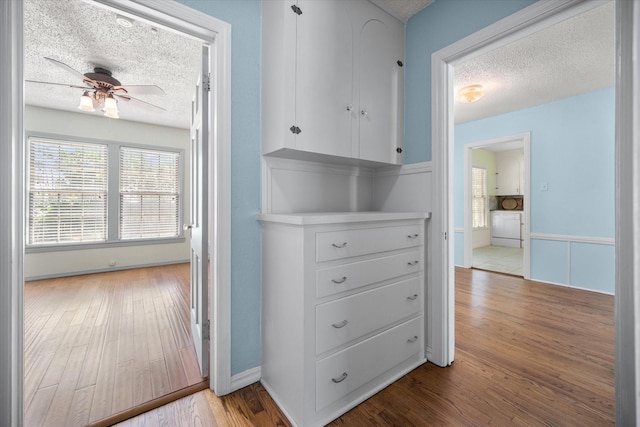 hall featuring a textured ceiling, wood finished floors, and baseboards