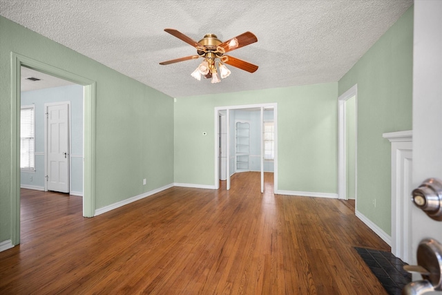 unfurnished living room featuring a ceiling fan, wood finished floors, a textured ceiling, and baseboards