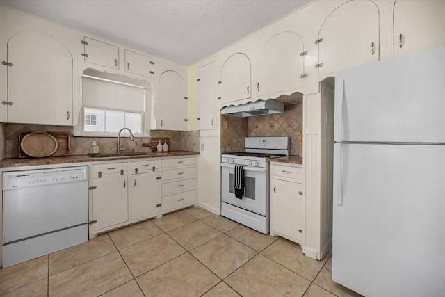 kitchen with white appliances, a sink, under cabinet range hood, tasteful backsplash, and white cabinets