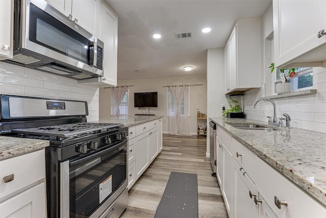 3444 Kellogg Ave, Dallas, TX 75216 - kitchen with stainless steel appliances, a sink, white cabinets, recessed lighting, and light wood-style floors