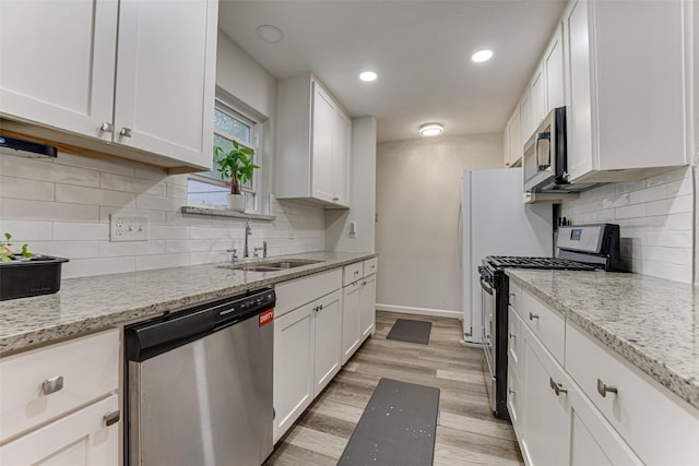 3444 Kellogg Ave, Dallas, TX 75216 - kitchen with appliances with stainless steel finishes, a sink, white cabinets, light wood-style flooring, and recessed lighting