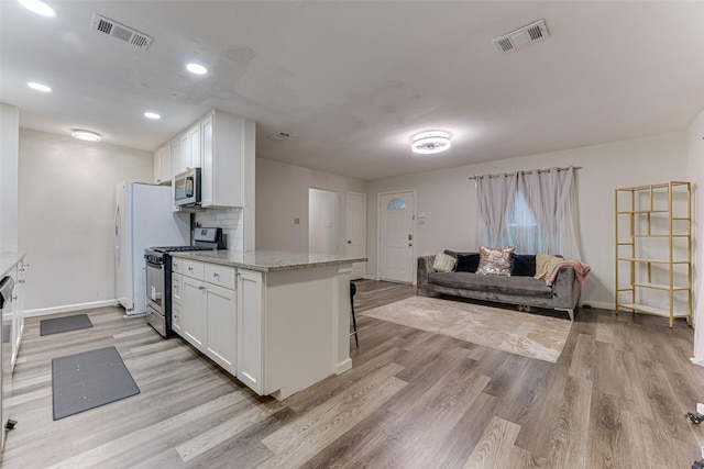 3444 Kellogg Ave, Dallas, TX 75216 - kitchen with stainless steel appliances, white cabinetry, light wood-style floors, baseboards, and recessed lighting