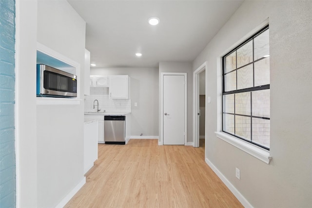 2833 Miller Pl, Mesquite, TX 75150 - kitchen with appliances with stainless steel finishes, a sink, white cabinetry, light wood finished floors, and decorative backsplash