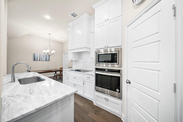 481 Washington Ave, Waxahachie, TX 75165 - kitchen with stainless steel appliances, a sink, dark wood-type flooring, decorative backsplash, and white cabinetry