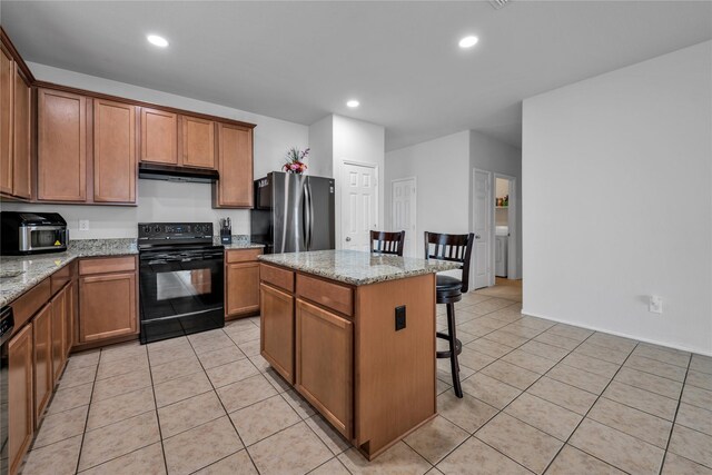 2336 Bermont Red Ln, Fort Worth, TX 76131 - kitchen with black / electric stove, freestanding refrigerator, under cabinet range hood, a kitchen breakfast bar, and a kitchen island