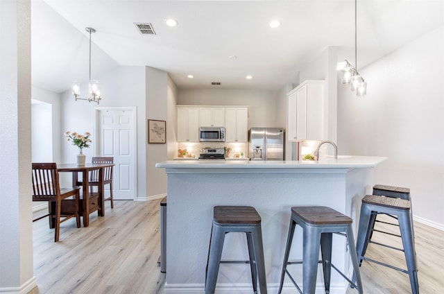 2836 Dawn Spring Dr, Little Elm, TX 75068 - kitchen with appliances with stainless steel finishes, light wood-style floors, a kitchen bar, white cabinets, and recessed lighting