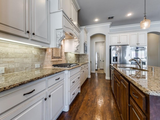 114 Crestbrook Dr, Rockwall, TX 75087 - kitchen featuring arched walkways, appliances with stainless steel finishes, a sink, white cabinets, and light stone counters