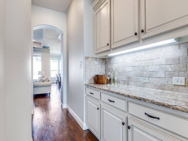 114 Crestbrook Dr, Rockwall, TX 75087 - kitchen featuring arched walkways, dark wood-type flooring, baseboards, backsplash, and light stone counters