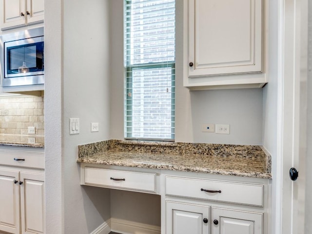 114 Crestbrook Dr, Rockwall, TX 75087 - kitchen featuring stainless steel microwave, tasteful backsplash, white cabinets, and light stone countertops