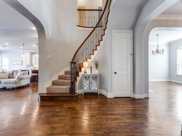 114 Crestbrook Dr, Rockwall, TX 75087 - foyer entrance featuring arched walkways, stairs, wood finished floors, a chandelier, and crown molding