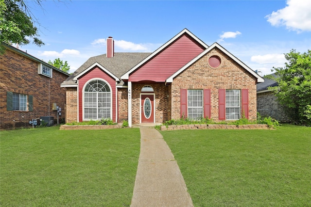 view of front of property featuring a front yard, a chimney, and brick siding