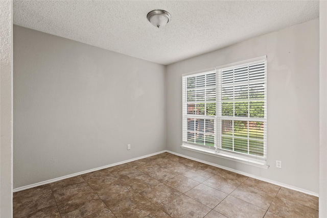 unfurnished room with a textured ceiling and baseboards