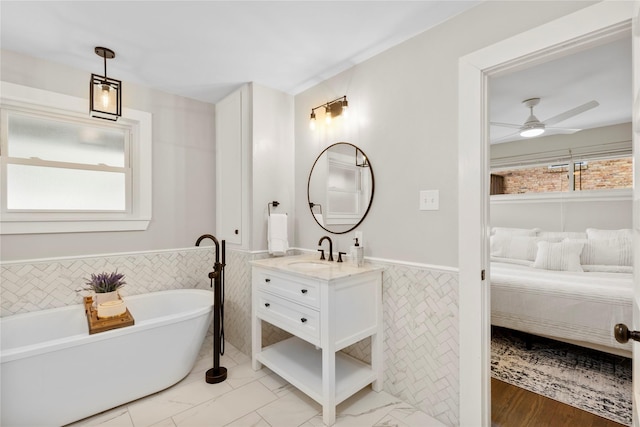 9031 Fringewood Dr, Dallas, TX 75228 - bathroom with wainscoting, tile walls, vanity, a freestanding tub, and a ceiling fan