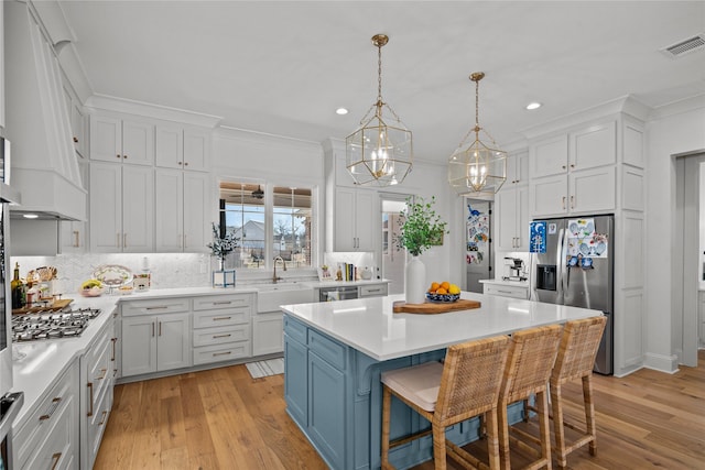 kitchen featuring stainless steel appliances, a sink, light countertops, recessed lighting, and a center island
