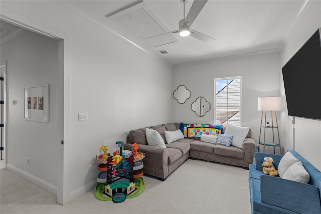 carpeted living area featuring a ceiling fan, attic access, and baseboards