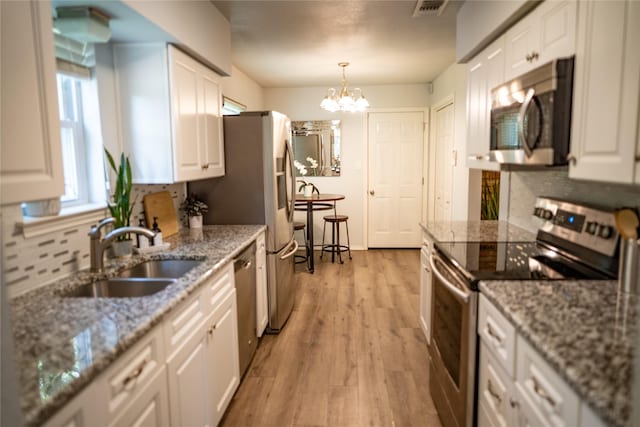 710 Melrose Dr, Richardson, TX 75080 - kitchen with stainless steel appliances, a sink, white cabinets, a chandelier, and light wood finished floors
