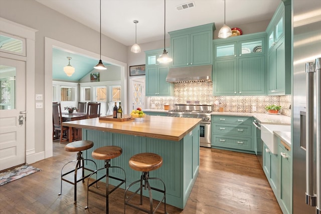 404 E Wall St, Grapevine, TX 76051 - kitchen featuring high quality appliances, under cabinet range hood, wood counters, tasteful backsplash, and a kitchen island