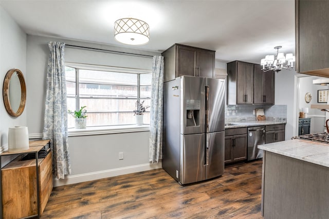 309 Westpark Dr N, Mckinney, TX 75071 - kitchen with appliances with stainless steel finishes, a chandelier, dark wood-style floors, light stone countertops, and decorative backsplash