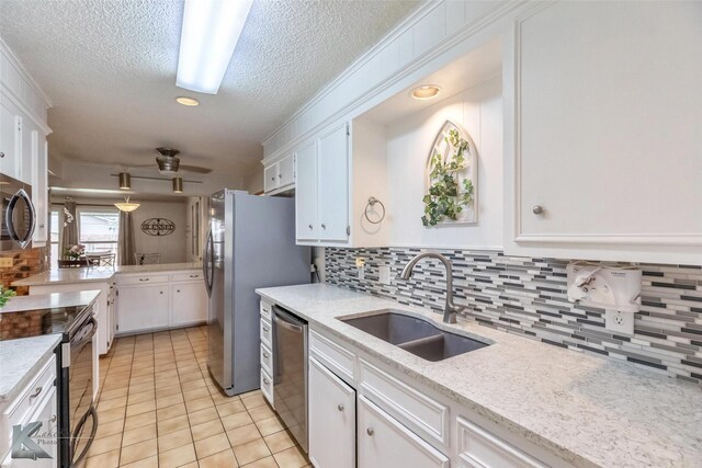 1001 Chriswood Dr, Abilene, TX 79601 - kitchen featuring a sink, stainless steel appliances, white cabinetry, a textured ceiling, and tasteful backsplash