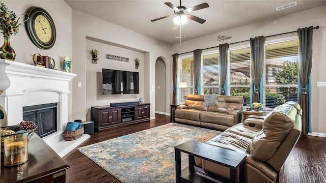 4209 Autumn Path Rd, Denton, TX 76208 - living area with a ceiling fan, arched walkways, dark wood-style flooring, and a fireplace with raised hearth