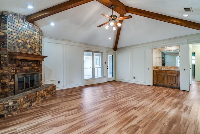 3506 Carla Dr, Rowlett, TX 75088 - unfurnished living room featuring a decorative wall, ceiling fan, a brick fireplace, and light wood-style flooring