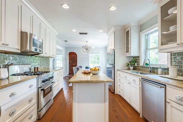6802 Hammond Ave, Dallas, TX 75223 - kitchen with appliances with stainless steel finishes, a sink, a kitchen island, a chandelier, and dark wood-type flooring