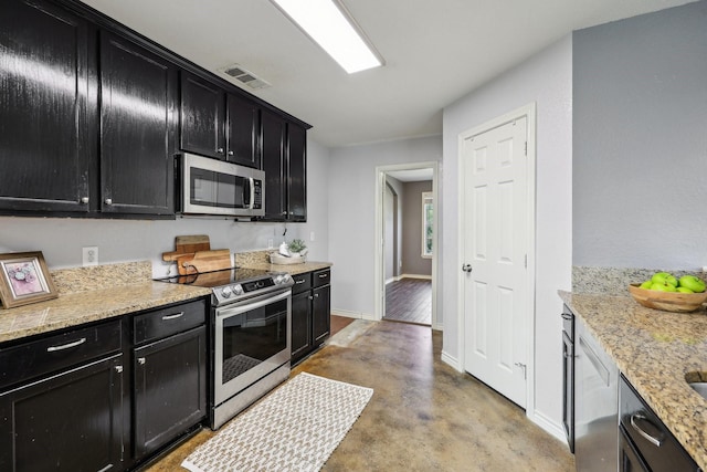 8808 Eastwood Ave, Cross Roads, TX 76227 - kitchen with stainless steel appliances, dark cabinetry, baseboards, concrete floors, and light stone countertops