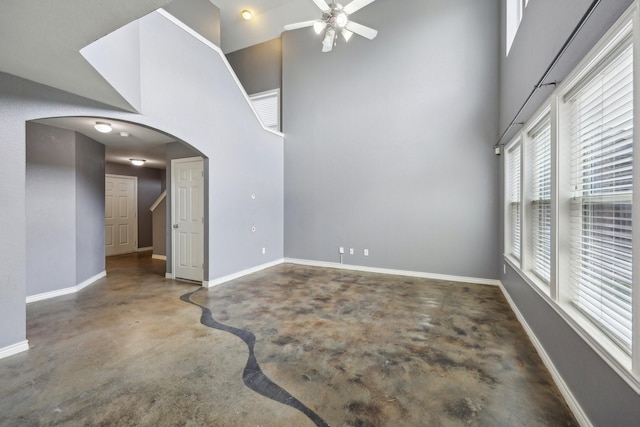 8808 Eastwood Ave, Cross Roads, TX 76227 - unfurnished room featuring concrete flooring, ceiling fan, a towering ceiling, arched walkways, and baseboards
