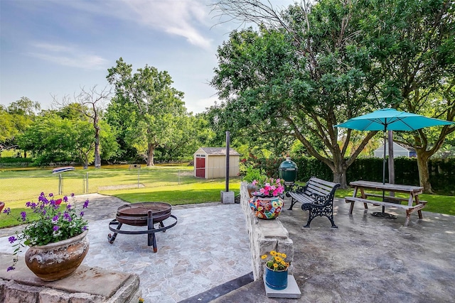 725 Bluebird St, Fort Worth, TX 76140 - view of patio / terrace featuring a fire pit, a storage unit, an outdoor structure, and view of wooded area