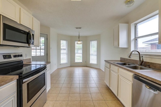 307 Apache Trl, Alvarado, TX 76009 - kitchen with stainless steel appliances, a sink, light tile patterned flooring, a textured ceiling, and white cabinetry