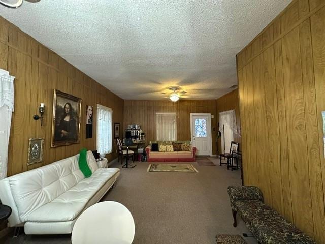 301 Dogwood Ave, Princeton, TX 75407 - living area featuring a textured ceiling, ceiling fan, wooden walls, and carpet flooring