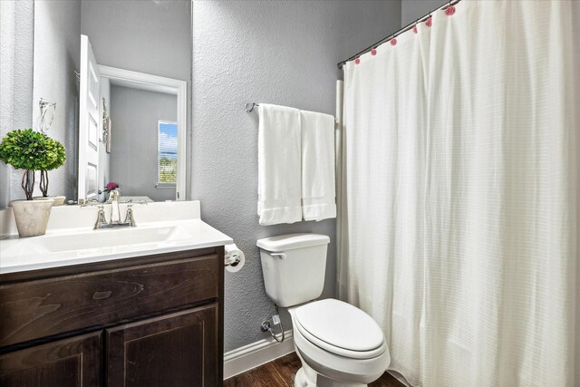 1946 Bel Air Dr, Arlington, TX 76010 - full bathroom featuring wood finished floors, toilet, a textured wall, baseboards, and vanity