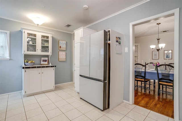 4016 El Campo Ave, Fort Worth, TX 76107 - kitchen with freestanding refrigerator, ornamental molding, a chandelier, tile counters, and white cabinets