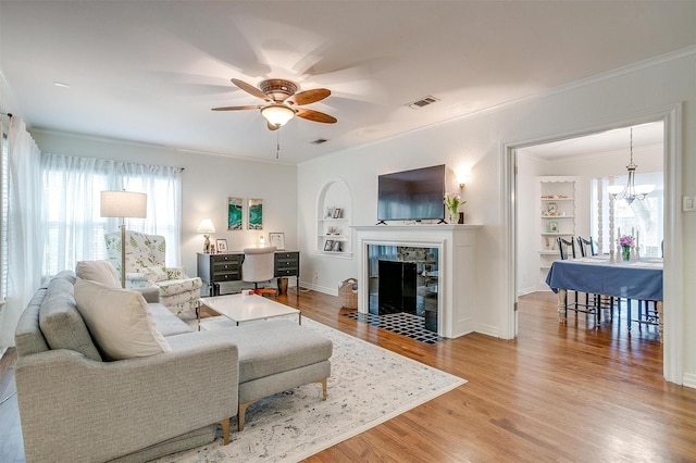 4016 El Campo Ave, Fort Worth, TX 76107 - living room featuring built in shelves, a ceiling fan, light wood finished floors, ornamental molding, and a fireplace