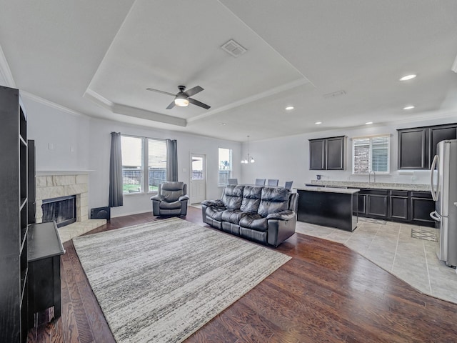 905 Jonius Creek Dr, Little Elm, TX 75068 - living area with ceiling fan, a raised ceiling, a fireplace, light wood finished floors, and recessed lighting