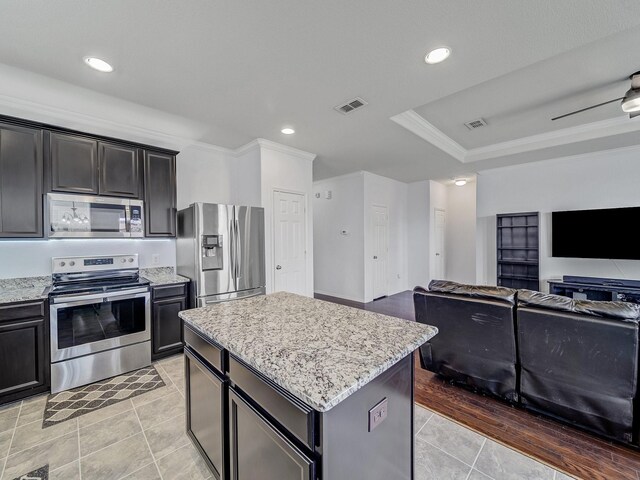 905 Jonius Creek Dr, Little Elm, TX 75068 - kitchen featuring appliances with stainless steel finishes, open floor plan, crown molding, a center island, and light tile patterned flooring