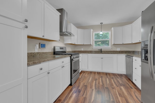 1507 Linda St, Bowie, TX 76230 - kitchen featuring appliances with stainless steel finishes, wall chimney exhaust hood, white cabinetry, wood finished floors, and light stone counters