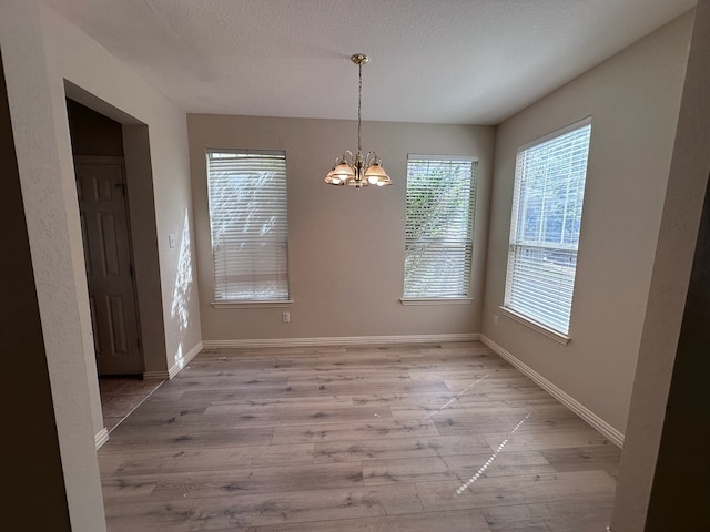 1026 Elm Dr, Providence Village, TX 76227 - unfurnished dining area with a chandelier, healthy amount of natural light, and light wood-style flooring