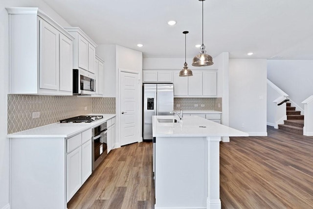 317 Boston Dr, Princeton, TX 74507 - kitchen featuring stainless steel appliances, wood finished floors, light countertops, backsplash, and a center island with sink