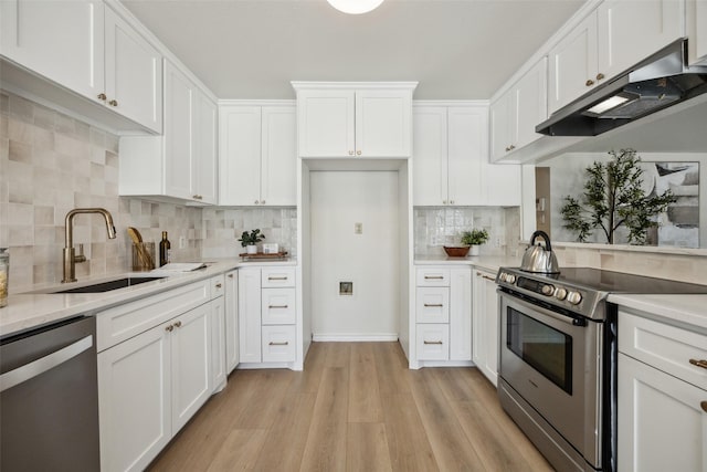 8803 Daytonia Ave, Dallas, TX 75218 - kitchen featuring appliances with stainless steel finishes, under cabinet range hood, a sink, light wood-type flooring, and white cabinetry