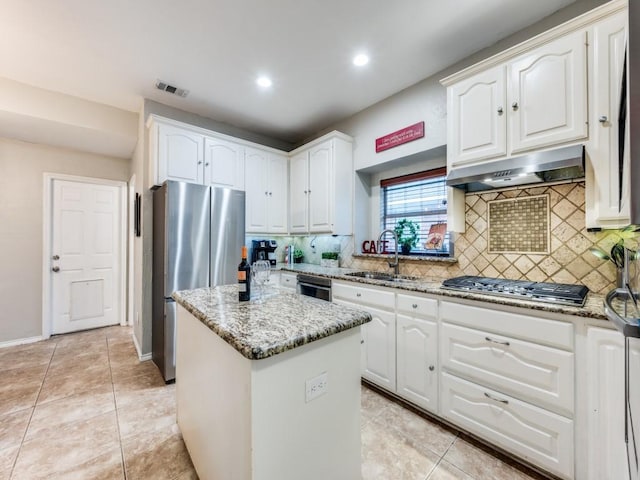 kitchen with under cabinet range hood, a sink, appliances with stainless steel finishes, light stone countertops, and tasteful backsplash