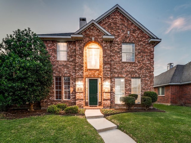 traditional-style home featuring brick siding and a front lawn