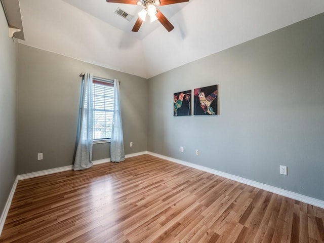 empty room featuring a ceiling fan, wood finished floors, baseboards, and vaulted ceiling