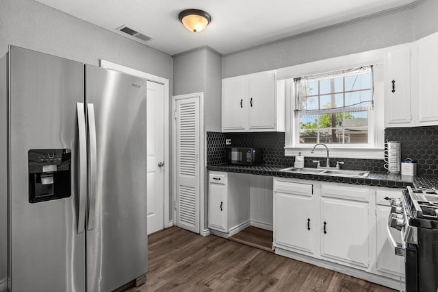 1709 Irving Lee St, Waco, TX 76711 - kitchen featuring stainless steel appliances, a sink, dark countertops, tasteful backsplash, and white cabinets