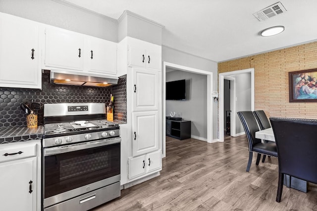 1709 Irving Lee St, Waco, TX 76711 - kitchen featuring stainless steel range with gas cooktop, exhaust hood, white cabinets, tasteful backsplash, and light wood-style floors