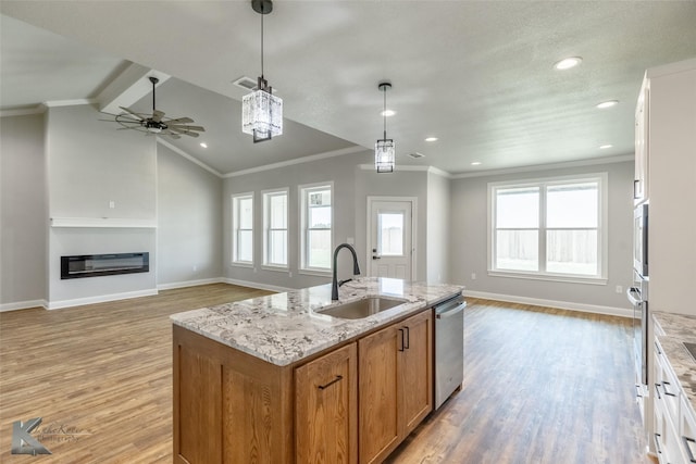 6718 Windmill Grass Ln, Abilene, TX 79606 - kitchen featuring a sink, stainless steel dishwasher, open floor plan, light wood finished floors, and a glass covered fireplace