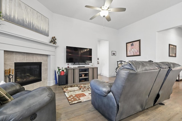 living area featuring wood finished floors, a ceiling fan, a tile fireplace, and baseboards