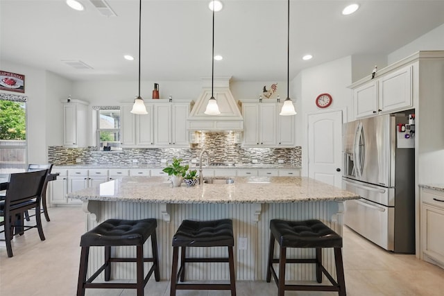 3604 Mendocino Trl, Mckinney, TX 75070 - kitchen featuring stainless steel fridge, healthy amount of natural light, tasteful backsplash, premium range hood, and recessed lighting