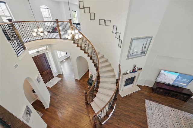 3604 Mendocino Trl, Mckinney, TX 75070 - entrance foyer featuring arched walkways, wood finished floors, a high ceiling, baseboards, and a premium fireplace
