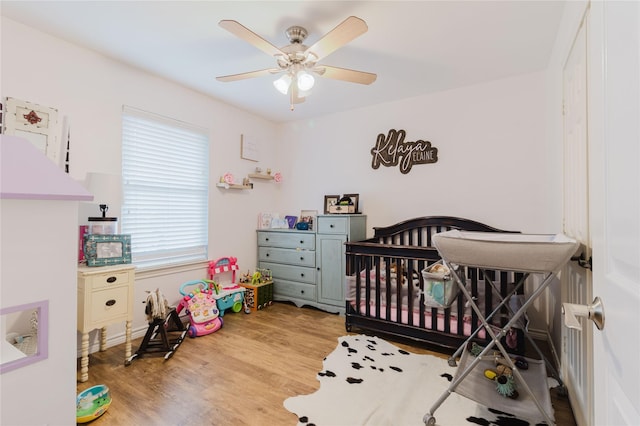 1003 E Burnett St, Ennis, TX 75119 - bedroom featuring wood finished floors, a crib, and a ceiling fan